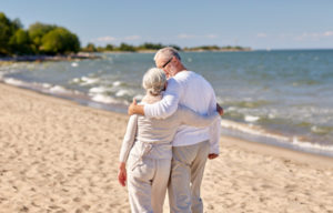 An older couple enjoy a stroll down the beach. Many couples downsize from the big properties and find life in a UPA retirement village a lot more relaxing.
